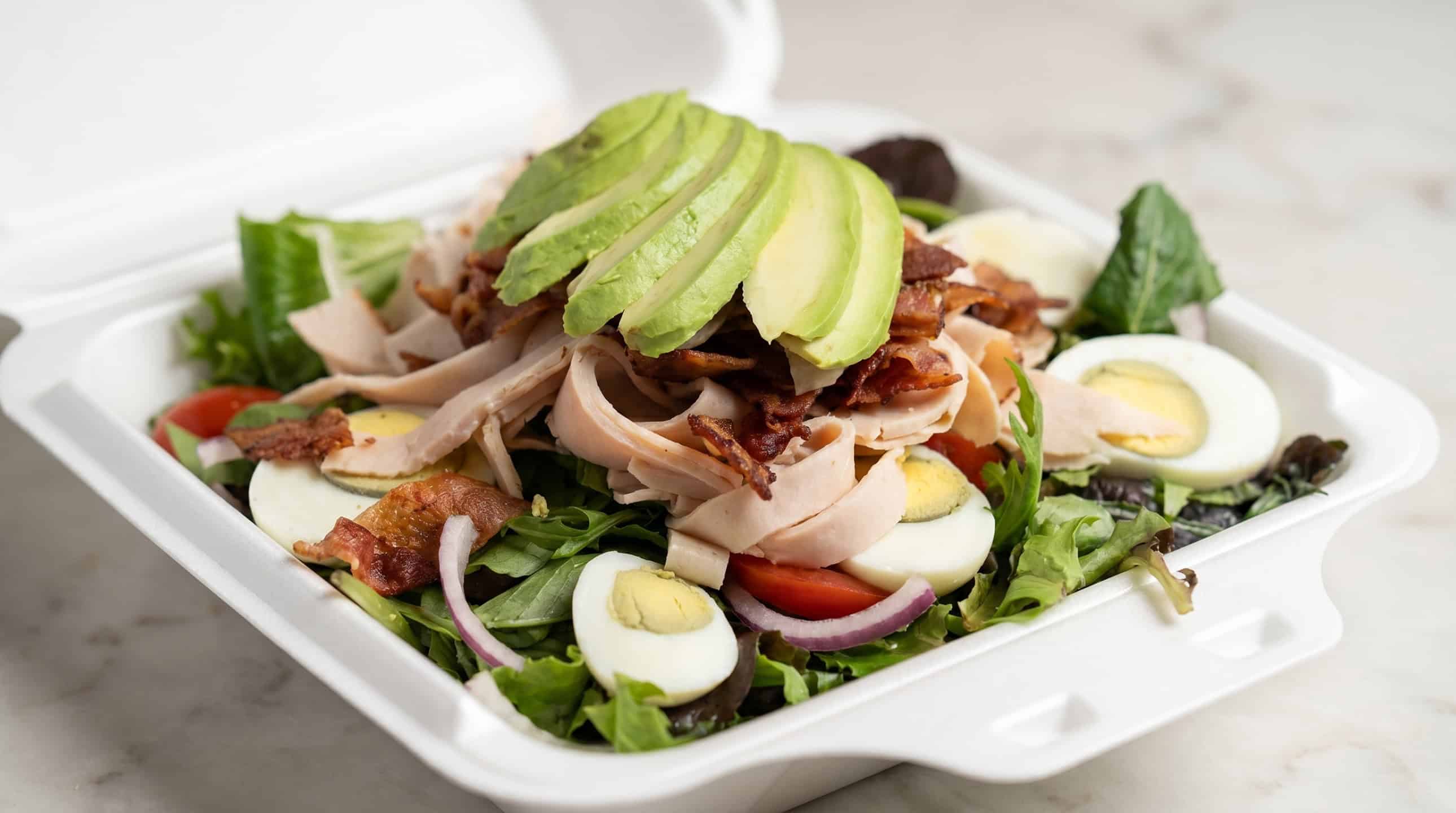 Cobb-style chef salad with turkey, bacon, avocado, hard-boiled egg, tomato, and mixed greens